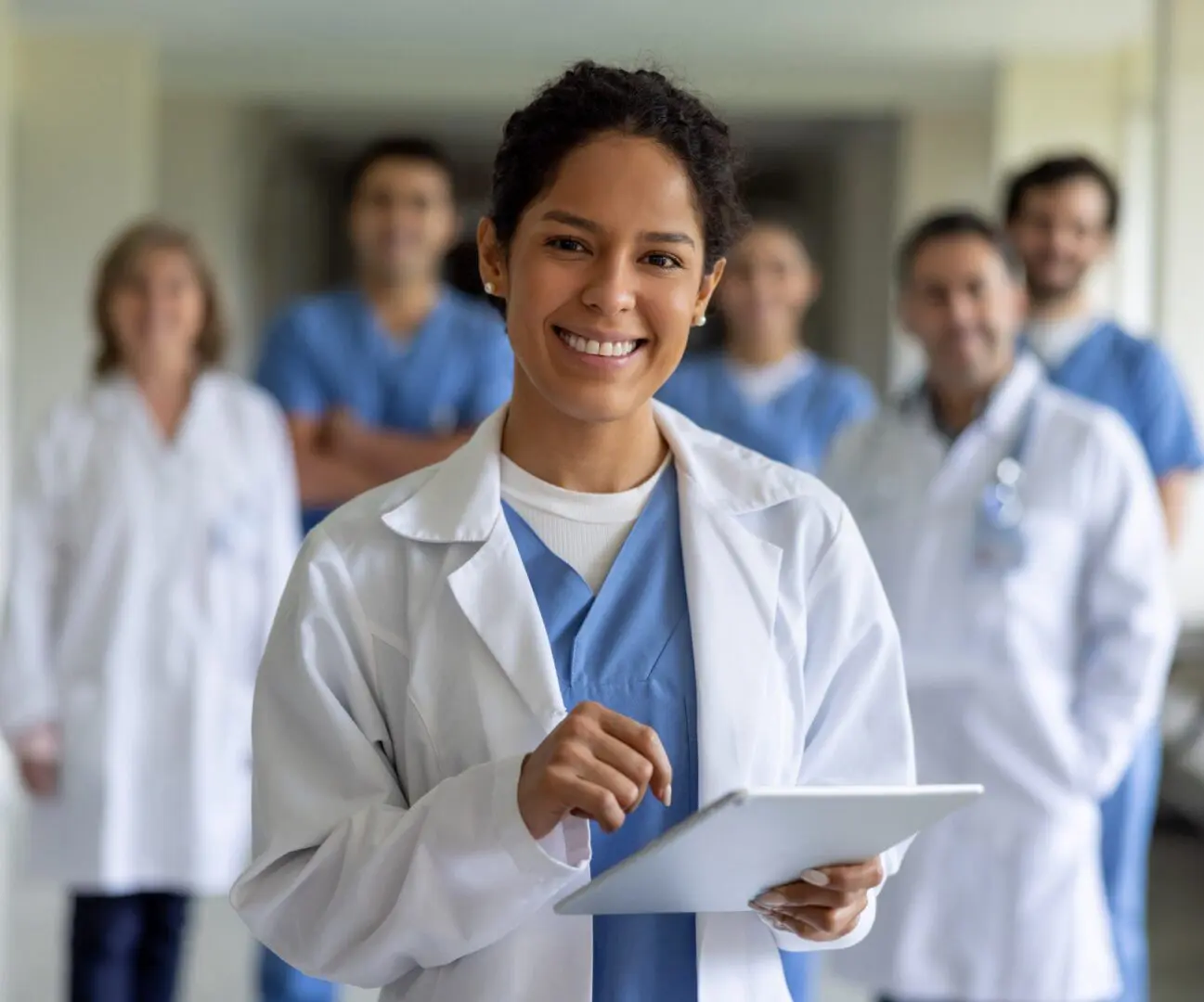 Doctor holding a tablet, team behind