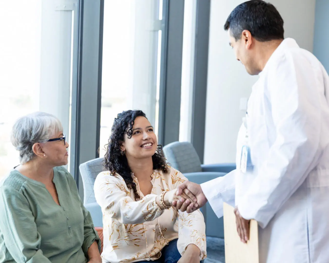 Doctor greeting two women in office